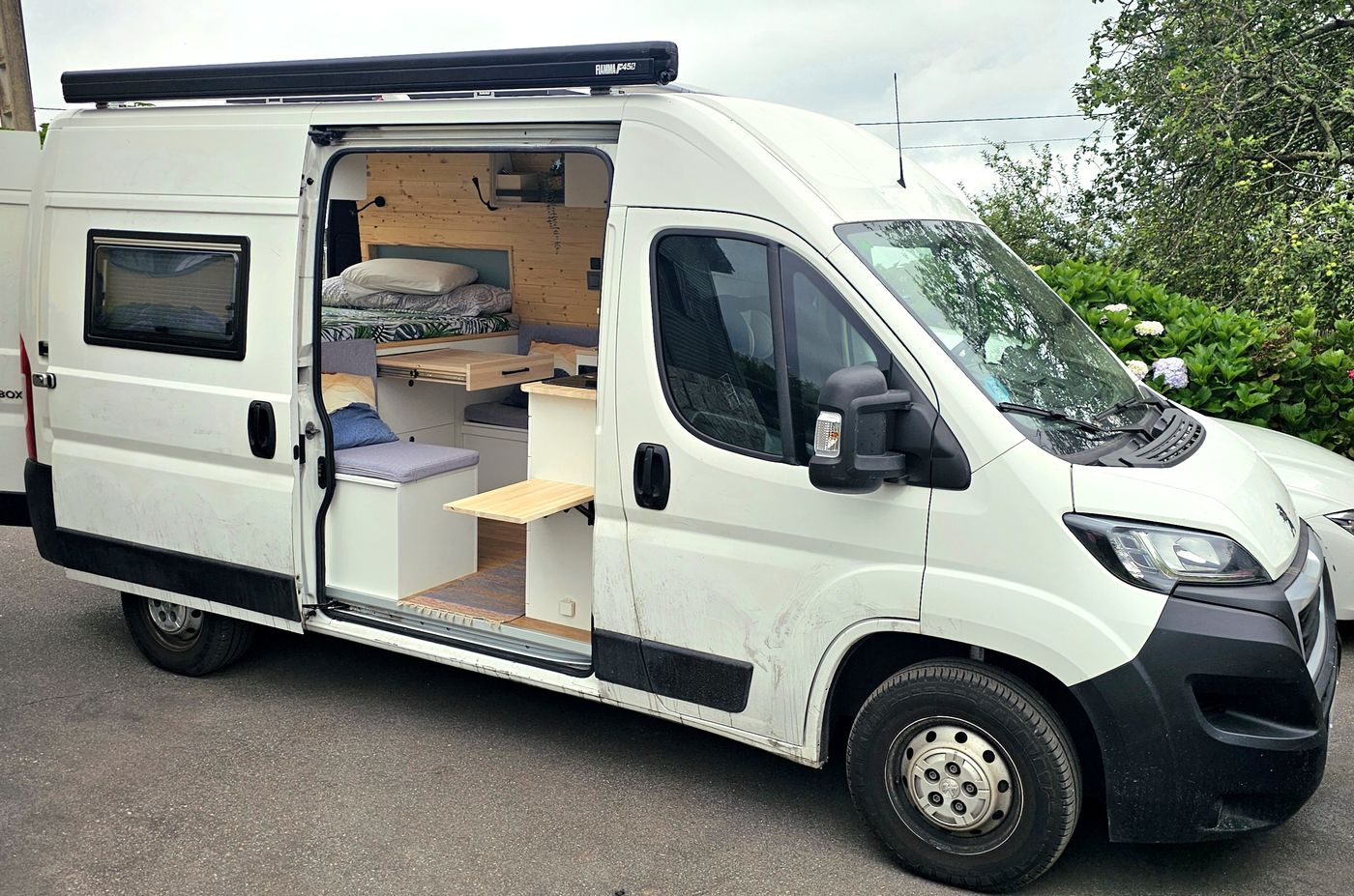 Furgoneta camper blanca con toldo y puerta lateral abierta