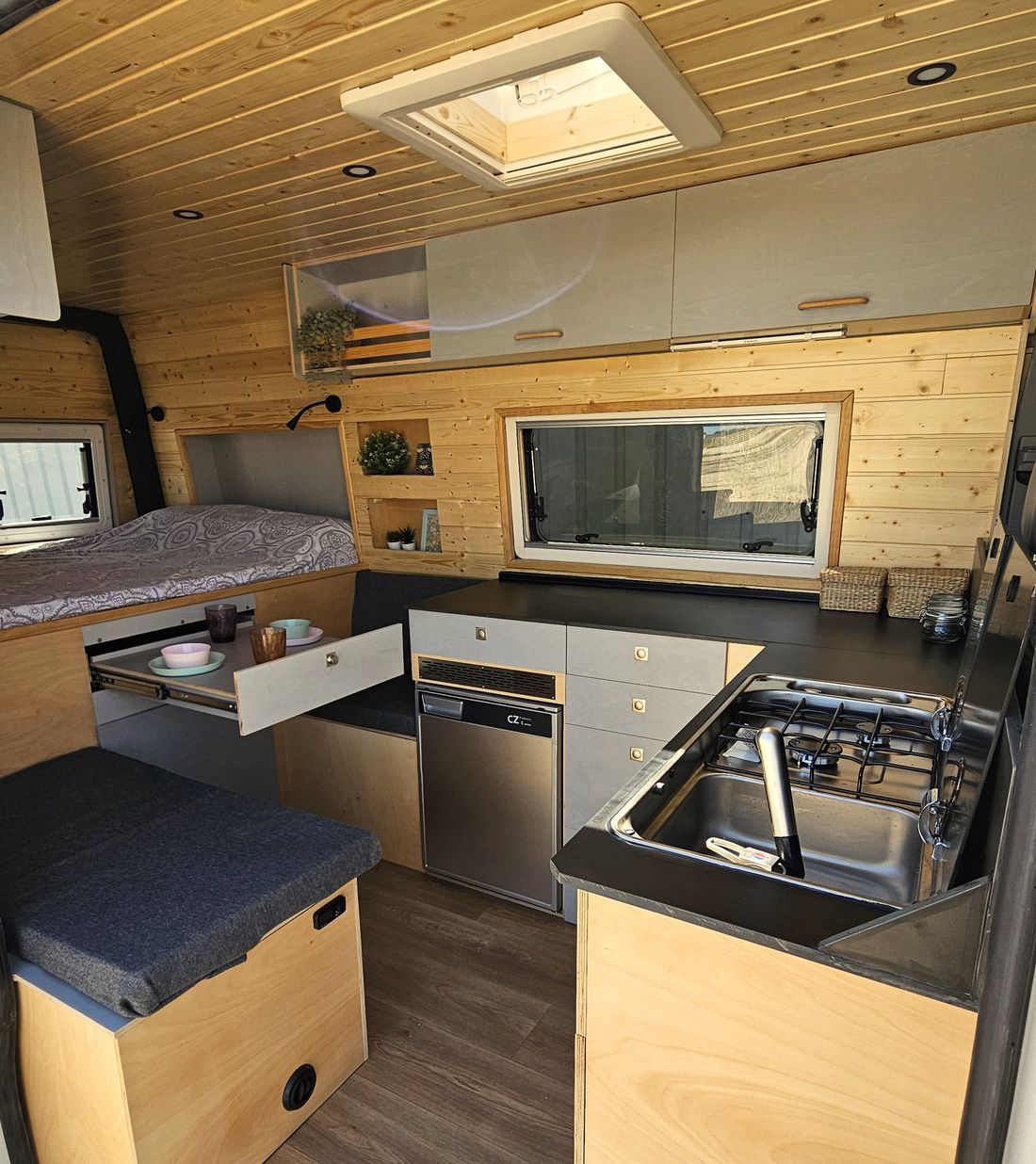 Cocina con fregadero, nevera y cajones junto a la cama