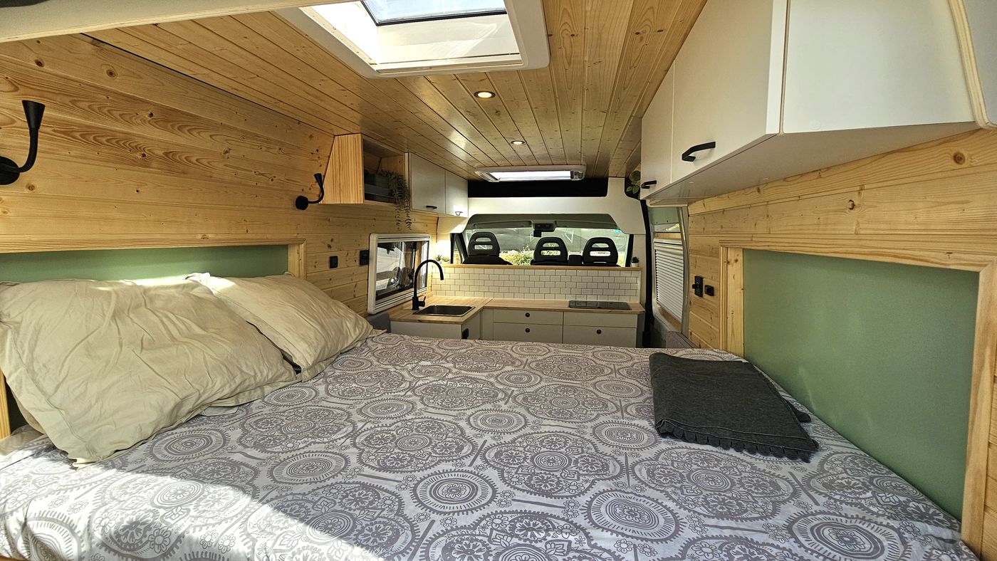 Interior con cama, techo de madera y claraboya